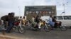 People ride motorcycles past a banner promoting the Eighth D-8 Summit in Islamabad November 21, 2012.