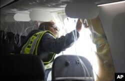 En esta fotografía publicada por la Junta Nacional de Seguridad en el Transporte, el investigador a cargo de la NTSB, John Lovell, examina el área del tapón del fuselaje del vuelo 1282 de Alaska Airlines el domingo 7 de enero de 2024 en Portland, Oregon, EEUU.