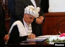 FILE - Afghan President Ashraf Ghani signs a peace agreement with Hizb-i-Islami, led by Gulbuddin Hekmatyar, in Kabul, Afghanistan, Sept. 29, 2016.