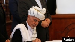 FILE - Afghan President Ashraf Ghani signs a peace agreement with Hizb-i-Islami, led by Gulbuddin Hekmatyar, in Kabul, Afghanistan, Sept. 29, 2016.