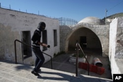 FILE - A masked Palestinian youth walks into Joseph's Tomb during clashes with Israeli troops nearby, in the West Bank city of Nablus, April 24, 2011.