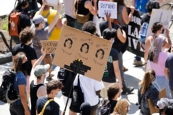 FILE - A protester carries a "Justice for Breonna Taylor" sign during a Defund the Police march from King County Youth Jail to City Hall in Seattle, Washington, Aug. 5, 2020.