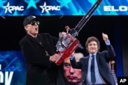 Elon Musk, left, receives a chainsaw from Argentina's President Javier Milei as they arrive speaks at the Conservative Political Action Conference, CPAC, at the Gaylord National Resort & Convention Center, Feb. 20, 2025, in Oxon Hill, Md.