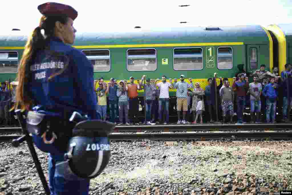 A police officer stands guard as migrants stage a protest in front of a train at Bicske railway station, Hungary, Sept. 4, 2015