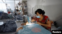 FILE - Workers wear protective masks at a private Ngoc Nu factory which makes blankets, pillows and mattresses for the local market, in Hanoi, June 1, 2020.