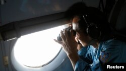 Military officer Pham Tuan Minh looks through a window of a Vietnam Air Force AN-26 aircraft during a mission to find the missing Malaysia Airlines flight MH370, off Con Dao island March 13, 2014.