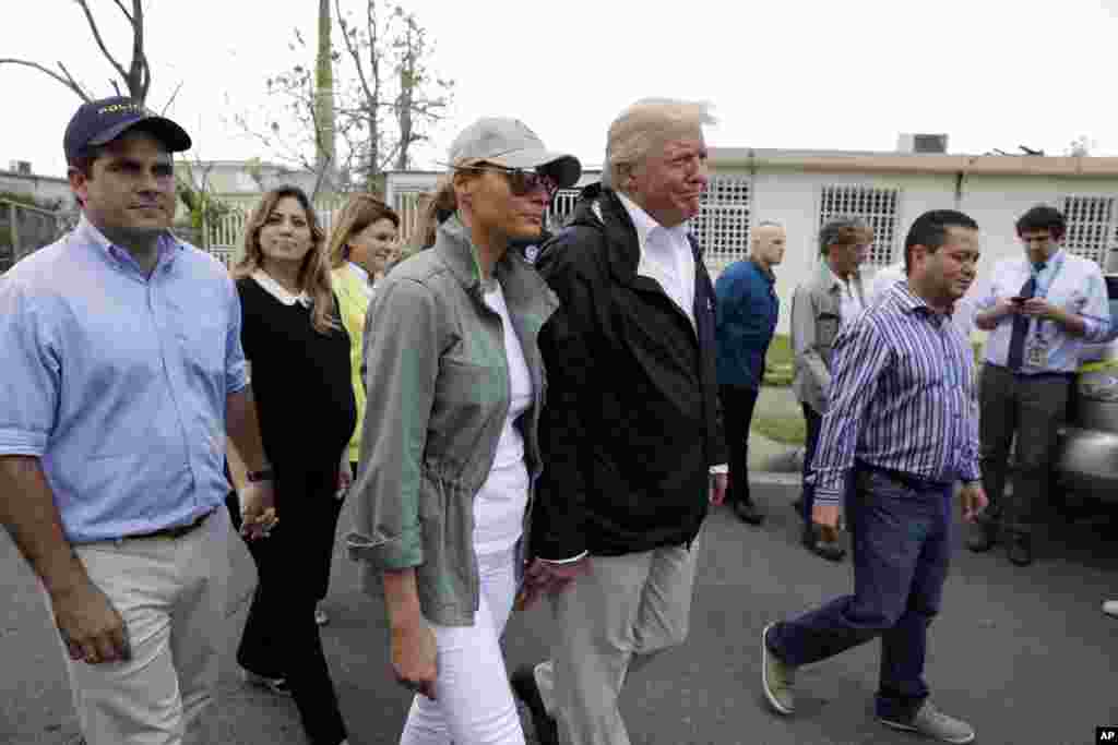 President Donald Trump and first lady Melania Trump take a walking tour with Puerto Rico Governor Ricardo Rosselló, left, and his wife Beatriz Areizaga, to survey hurricane damage and recovery efforts in a neighborhood in Guaynabo, Puerto Rico, Oct. 3, 20