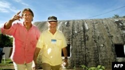 El actor estadounidense Christopher Kennedy Lawford (izquierda) posa con el capitán retirado de la Marina estadounidense William Ecker , afuera de un silo donde se ensamblaban misiles nucleares R-12 en La Habana, Cuba, el 13 de octubre de 2002. Foto: AFP/Adalberto Roque.