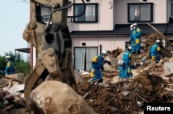 Rescue workers search for missing people at a landslide site caused by heavy rain in Kumano Town, Hiroshima Prefecture, Japan, July 11, 2018.