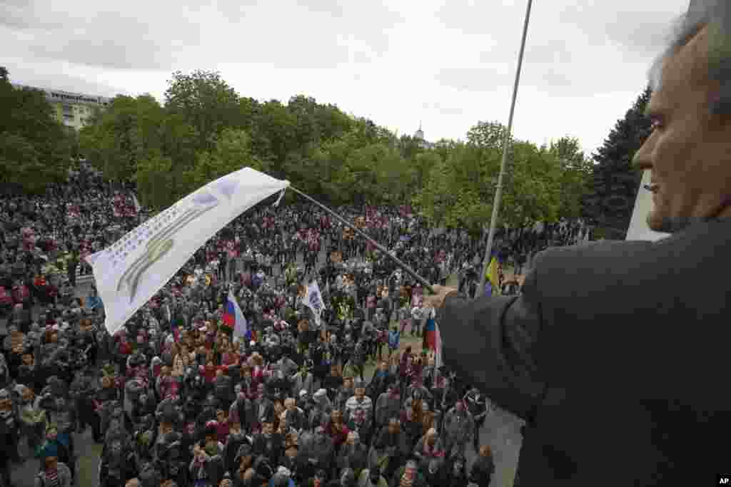 A pro-Russian activist waves a Donbas Republic flag over a crowd celebrating the capture of an administration building in the center of Luhansk, April 29, 2014.