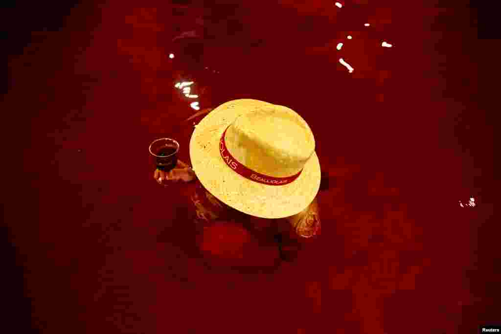 A woman drinks wine in a hot bath with colored water representing wine at the Hakone Kowaki-en Yunessun spa resort during an event marking Beaujolais Nouveau Day in Hakone west of Tokyo, Japan.