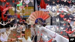 A robot holding a paper fan among "origami" paper cranes is shown at the China International Import Expo in Shanghai, Monday, November 5, 2018. (AP Photo/Ng Han Guan)