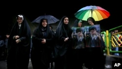 Iranian women attend a rally marking the 40th anniversary of the 1979 Islamic Revolution, as two of them hold pictures of Iranian Supreme Leader Ayatollah Ali Khamenei, in Tehran, Iran, Monday, Feb. 11, 2019. (AP Photo/Ebrahim Noroozi)