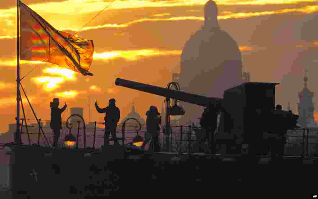 People walk near the front deck gun of the Aurora Cruiser, moored in St. Petersburg, Russia.