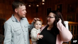 Lilly Ross holds her toddler son, Leonard, as she talks with face transplant recipient Andy Sandness, left, after their first meeting at the Mayo Clinic, Oct. 27, 2017, in Rochester, Minn.