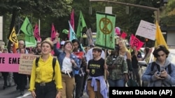 In this photo taken June 21, 2019, people demonstrating to raise awareness of climate change blocked streets in downtown Portland, Ore.