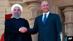 하산 로하니 이란 대통령(왼쪽)과 바르함 살리 이라크 대통령이 11일 이라크 바드다드의 살람궁에서 만나 악수하고 있다. 