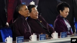 U.S. President Barack Obama, left, and Chinese President Xi Jinping, center, prepare to watch a firework show during the Asia-Pacific Economic Cooperation (APEC) summit in Beijing Monday, Nov. 10, 2014. At right is Xi's wife Peng Liyuan. (AP Photo/Wang 