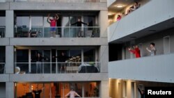 Des résidents font de l'exercice sur leur balcon à la avec des entraîneurs de fitness à Nantes, en France, pendant le confinement destiné à ralentir la propagation de la maladie à coronavirus (COVID-19) en France, le 27 mars 2020. REUTERS / Stephane Mahe