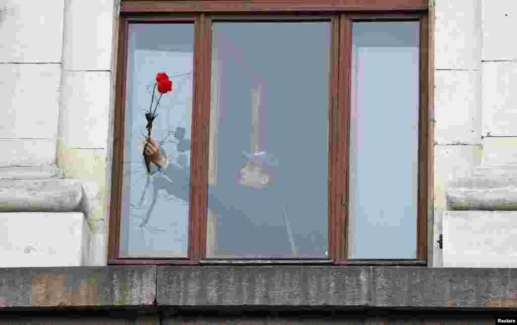 A man holds carnations through a broken window of a burnt trade union building, the site of recent street battles between pro-Russian and pro-Ukrainian supporters, in the Black Sea port of Odessa May 4, 2014. 