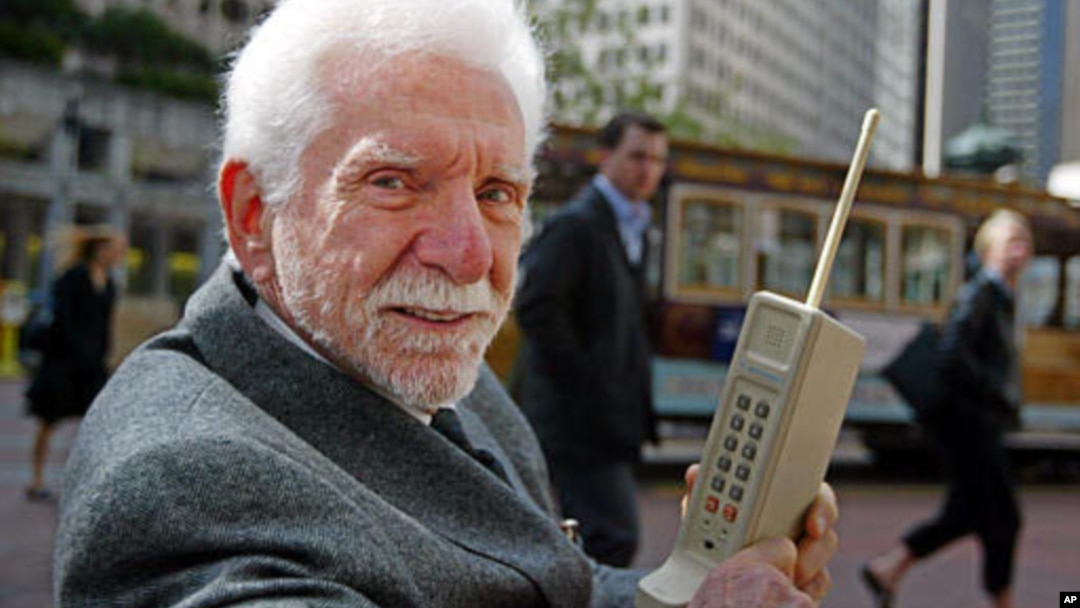Martin Cooper, difoto pada 2003, memegang model asli prototipe telepon yang ia pakai untuk membuat panggilan telepon pertama dari telepon selular pada 1973. (AP/Eric Risberg)