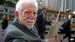 Martin Cooper, pictured here in 2003, holds the original model of the protype phone he used to make the first ever cell phone call in 1973.