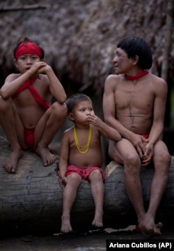 A group of Yanomami Indians sit in their village called Irotatheri in Venezuela's Amazon region, Friday, Sept. 7, 2012. (AP Photo/Ariana Cubillos)