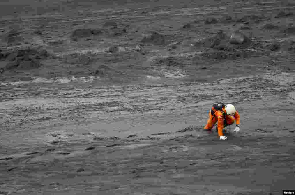 A rescue worker is stuck in mud after the burst of the Mount Semeru volcano, in Curah Kobokan, Indonesia.