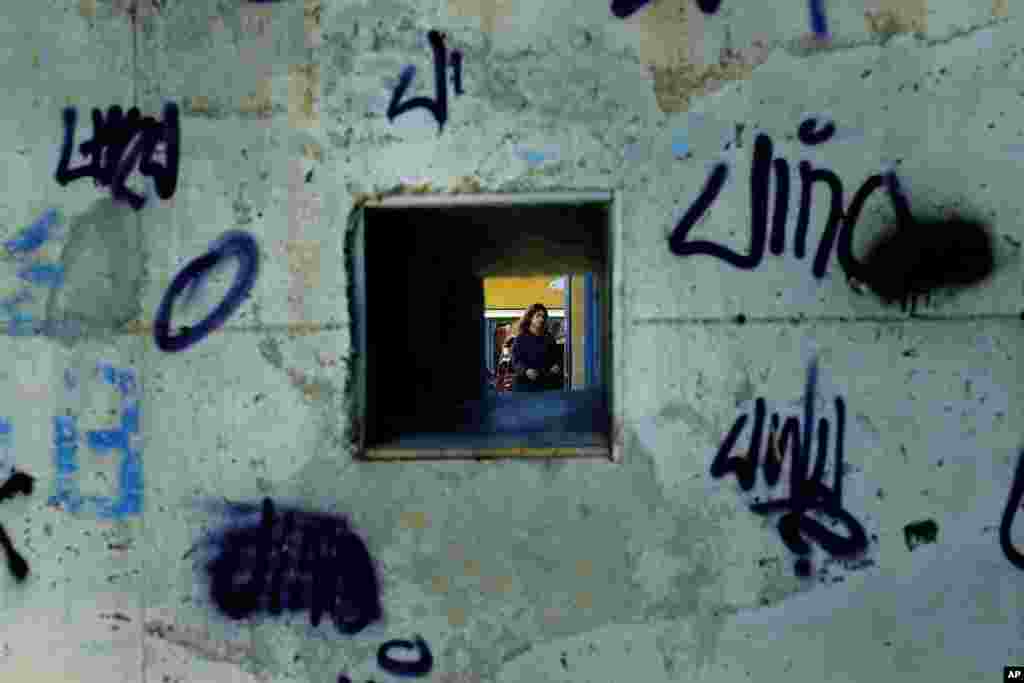 A woman is seen through a military battle position from a wall at the U.N buffer zone that divided the south, Greek Cypriot, and the north, Turkish Cypriot, breakaway controlled areas in the divided capital Nicosia, Cyprus.