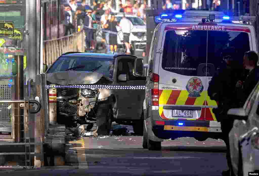 Australian police stand near a crashed vehicle after they arrested the driver of a vehicle that had ploughed into pedestrians at a crowded intersection near the Flinders Street train station in central Melbourne, Australia.