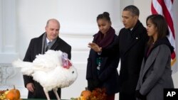 President Barack Obama, with daughters Sasha (left) and Malia, carries on the Thanksgiving tradition of saving Popcorn the turkey from the dinner table with a "presidential pardon," at the White House in Washington, Nov. 27, 2013.