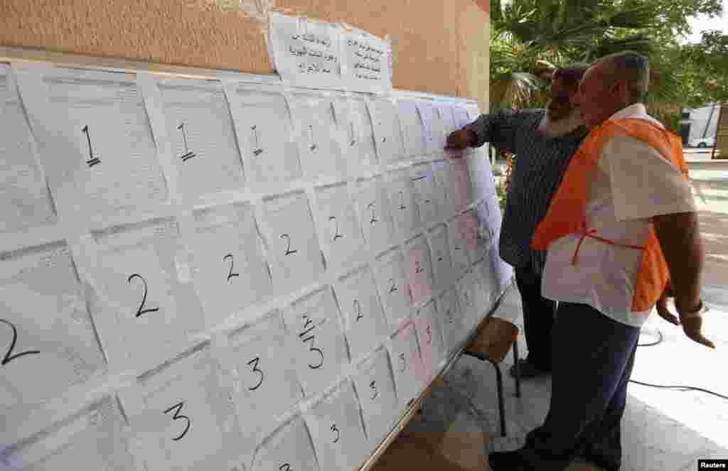 An official helps a voter find his name before voting inside a school in Tripoli, June 25, 2014. 