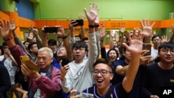 Election winner candidate Kelvin Lam, right, and pro-democracy activist Joshua Wong, second right, wave to people and thank for their support, outside South Horizons Station in Hong Kong, Monday, Nov. 25, 2019.