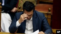 Perdana Menteri Alexis Tsipras membacakan catatannya pada pertemuan dengan parlemen di Athena, Kamis (16/7).