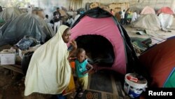 FILE - An African migrant sits with her son beside her tent at a makeshift camp set up under the bridge of a motorway on the outskirts of Algiers, Algeria, June 28, 2017. 