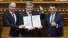 Ukrainian President Petro Poroshenko, center, Prime Minister Volodymyr Groysman, right, and parliament speaker Andriy Parubiy are seen with the newly signed Constitutional amendment on pursuing EU and NATO membership, in Ukraine's parliament in Kyiv, Feb. 19, 2019.