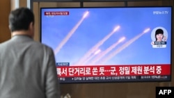 A man watches a television screen showing a news broadcast with file footage of a North Korean missile test, at a train station in Seoul on March 10, 2025.