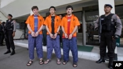 FILE - Suspected Islamic militants, from left to righ: Abdullah, Ahmet Mahmud and Abdulbasit Tuzer, escorted by police, wait for their transport to the prison after a sentencing hearing at North Jakarta District Court in Jakarta, Indonesia, July 13, 2015.