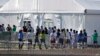 Niños inmigrantes centroamericanos hacen fila para entrar a una casa de campaña en el centro de detención temporal de Homested, Florida. [Foto: Archivo]
