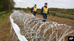 FILE - Hungarian police officers patrol an area at the temporary border fence positioned at the green border between Hungary and Croatia at Zakany, 234 km (145 miles) southwest of Budapest, Hungary, Sept. 30, 2015.