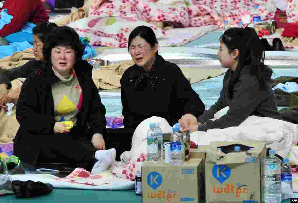 South Korean relatives of passengers on board a capsized ferry react as they wait for news at a gym in Jindo.