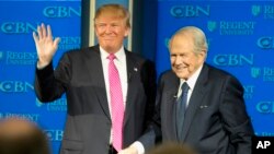 On Feb. 24, 2016, Republican presidential candidate, Donald Trump, accompanied by Rev. Pat Robertson, waves as he arrives for an appearance at Regent University in Virginia Beach, Virginia.
