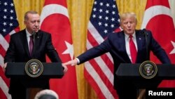 FILE - U.S. President Donald Trump reaches to Turkey's President Tayyip Erdogan during a joint news conference at the White House in Washington, November 13, 2019. 