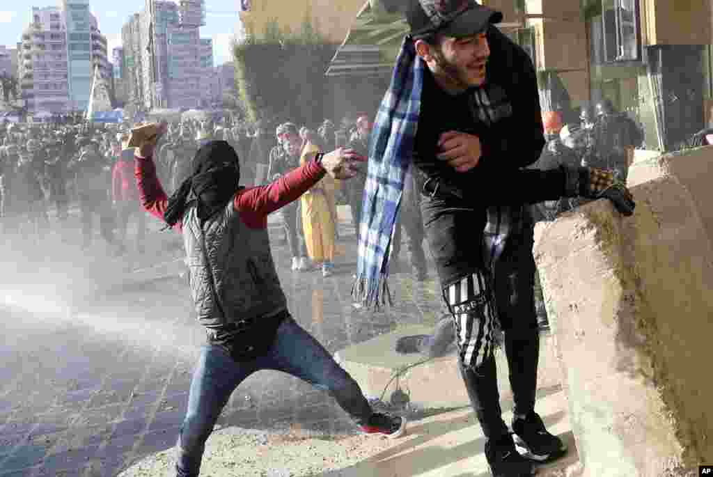 An anti-government protesters throw stones at police during a protest against a parliament session in downtown Beirut, Lebanon.