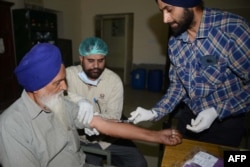 FILE - Indian doctor and specialists collecting DNA samples from Sardara Singh (L), whose son Gurcharan Singh went missing in Iraq, at the Forensic Medicine and Toxicology Department of the Government Medical College in Amritsar, Oct. 28, 2017.