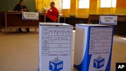Ballot boxes await voters as Election officials (background) await their arrival after they opened early for disabled people to vote in Nyanga township before Wednesdays official elections on the outskirts of the city of Cape Town, South Africa, May 5, 2