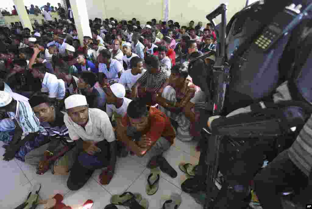 Polisi berjaga-jaga saat para pria etnis Rohingya yang baru tiba berkumpul di tempat penampungan sementara di Lhoksukon, Aceh (13/5). ​(AP/Binsar Bakkara)