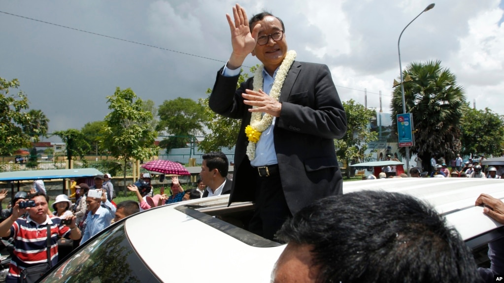 FILE - In this Aug. 16, 2015, file photo, Sam Rainsy, leader of the opposition Cambodia National Rescue Party (CNRP), waves from a car upon his arrival at Phnom Penh International Airport in Phnom Penh, Cambodia as hundreds of cheering supporters greeted him on his return from a trip abroad. The head of Cambodia's opposition party has announced his resignation from the group after the country's long-serving prime minister announced plans for a law that could lead to the party's dissolution. Rainsy announced his resignation Saturday, Feb. 11, 2017, in a letter to his Cambodia National Rescue Party.(AP Photo/Heng Sinith)