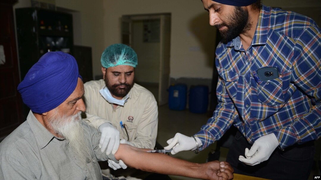 Dokter dan petugas medis India mengambil sampel darah Sardara Singh (kiri), untuk memastikan DNA anak laki-lakinya, Gurcharan Singh termasuk di antara 39 mayat yang ditemukan di Mosul, Irak. 