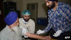 Dokter dan petugas medis India mengambil sampel darah Sardara Singh (kiri), untuk memastikan DNA anak laki-lakinya, Gurcharan Singh termasuk di antara 39 mayat yang ditemukan di Mosul, Irak. 